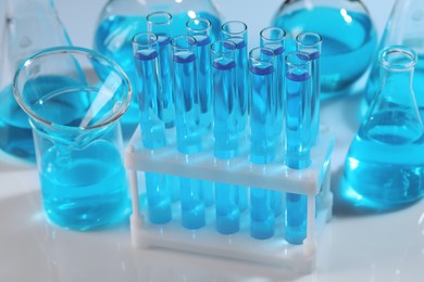 Laboratory glassware with blue liquid on light background