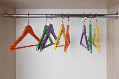 Set of bright clothes hangers on wardrobe rail