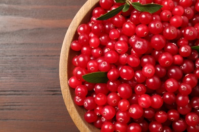 Photo of Tasty ripe cranberries on brown wooden table, top view