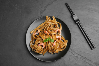 Photo of Tasty buckwheat noodles with shrimps on black table, flat lay