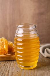 Jar of tasty aromatic honey on wooden table
