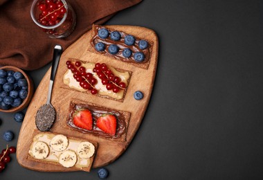 Photo of Fresh crunchy rye crispbreads with different toppings on black table, flat lay. Space for text