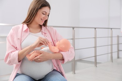 Pregnant woman with doll at courses for expectant mothers indoors
