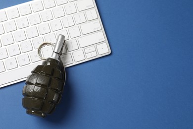 Photo of Grenade and computer keyboard on blue background, flat lay with space for text. Hybrid warfare concept
