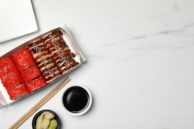 Photo of Food delivery. Delicious sushi rolls served on white marble table, flat lay with space for text