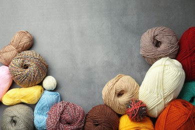 Different balls of woolen knitting yarns on grey background, flat lay. Space for text