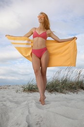 Beautiful woman in bikini with beach towel on sand