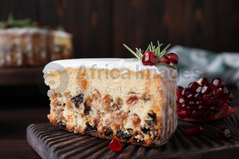 Photo of Piece of traditional homemade Christmas cake and fresh pomegranate on wooden board, closeup