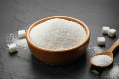 Granulated sugar in bowl on dark table