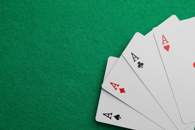 Four aces playing cards on green table, top view. Space for text