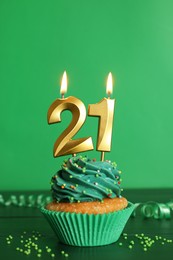 21th birthday. Delicious cupcake with number shaped candles for coming of age party on green wooden table