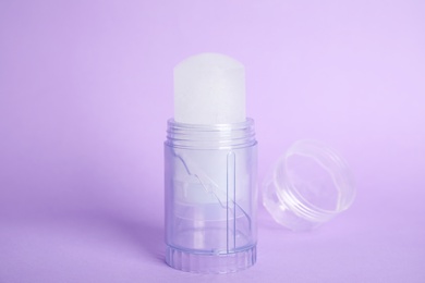 Natural crystal alum stick deodorant and cap on lilac background