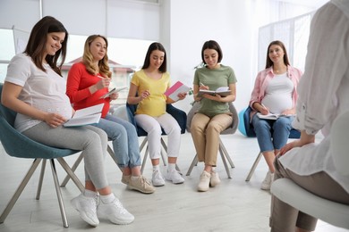 Group of pregnant women with midwife at courses for expectant mothers indoors