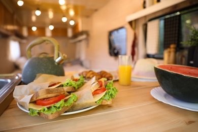 Delicious sandwiches and watermelon on wooden table in modern trailer. Camping vacation