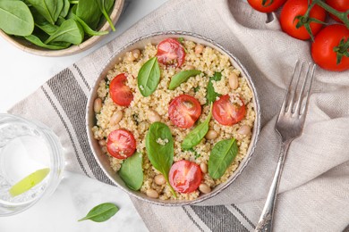 Photo of Delicious quinoa salad with tomatoes, beans and spinach leaves served on white table, flat lay