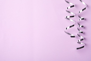 Shiny silver serpentine streamers on pink background, flat lay. Space for text