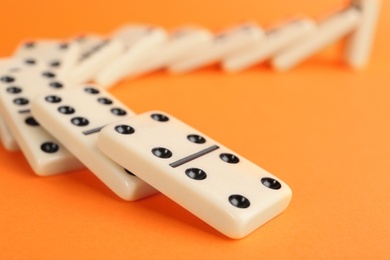 White domino tiles falling on orange background, closeup