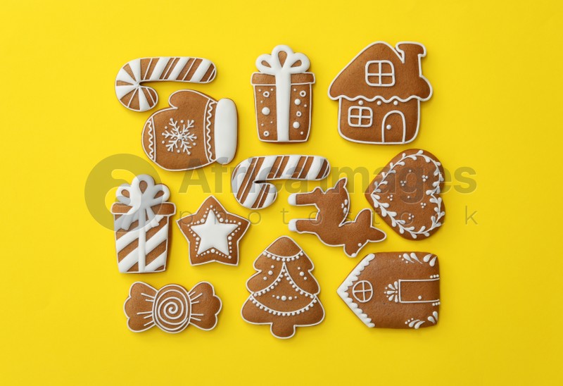 Different Christmas gingerbread cookies on yellow background, flat lay