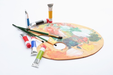 Wooden palette with brushes and acrylic paints on white background. Artistic equipment for children