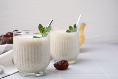 Photo of Glasses of delicious date smoothie with mint on white table. Space for text