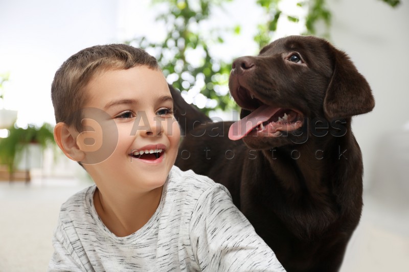 Little boy playing with puppy at home. Friendly dog