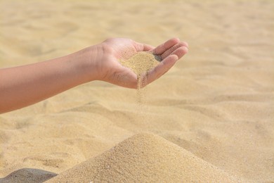 Child pouring sand from hand on beach, closeup with space for text. Fleeting time concept