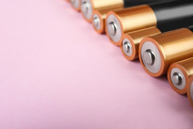 New AA batteries on pink background, closeup. Space for text