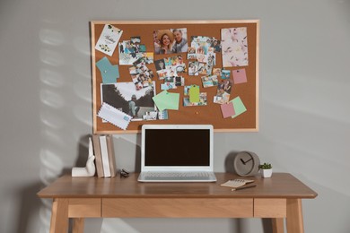 Stylish workplace with vision board and laptop