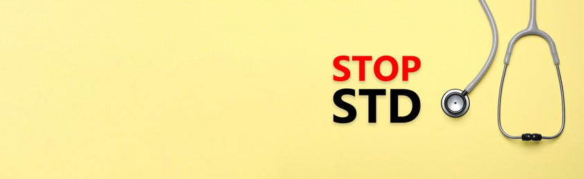 Text STOP STD and stethoscope on yellow background, top view with space for text. Banner design