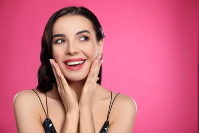 Portrait of surprised woman on pink background, space for text