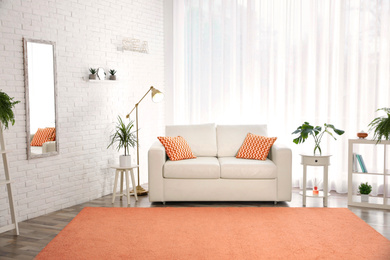 Stylish room interior with comfortable sofa and orange carpet