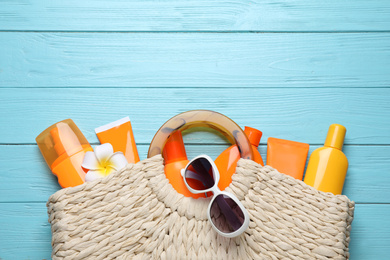 Sun protection products in bag on light blue wooden background, flat lay. Space for text