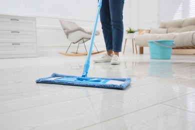 Woman cleaning parquet floor with mop at home, closeup