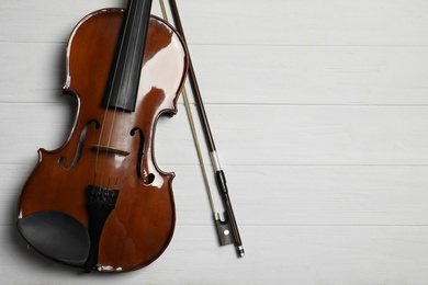Classic violin and bow on white wooden background, flat lay. Space for text