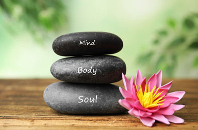 Stones with words Mind, Body, Soul and lotus flower on wooden table. Zen lifestyle