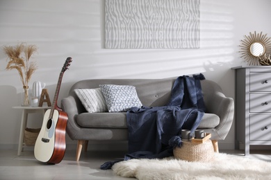 Photo of Comfortable sofa with soft plaid in stylish room interior