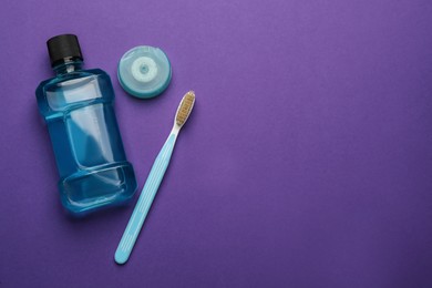 Mouthwash, toothbrush and dental floss  on purple background, flat lay. Space for text