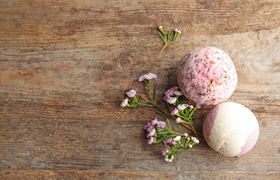 Photo of Flat lay composition with bath bombs, flowers and space for text on wooden background