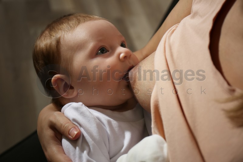 Young woman breast feeding her little baby at home, closeup