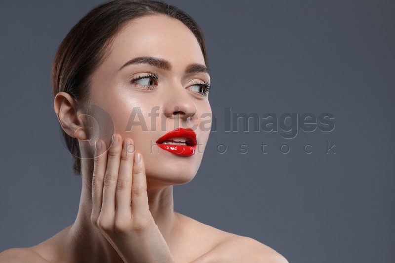 Young woman with beautiful red lips on grey background. Space for text