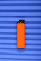 Photo of Stylish small pocket lighter on blue corrugated fiberboard, top view