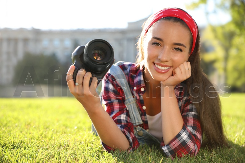 Photo of Young photographer with professional camera on green grass