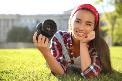 Young photographer with professional camera on green grass