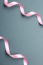Beautiful pink ribbons on grey background, flat lay. Space for text