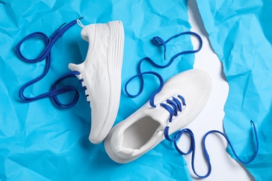 Pair of stylish shoes with laces on light blue paper, flat lay