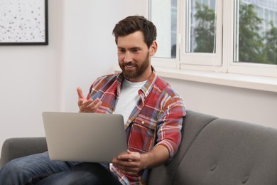 Bearded man having video chat on laptop indoors