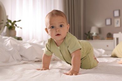 Cute baby crawling on bed at home