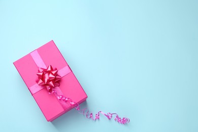 Pink gift box on light blue background, top view. Space for text