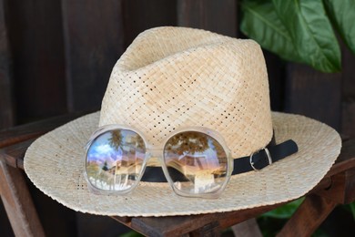 Stylish hat and sunglasses on wooden table, closeup. Beach accessories