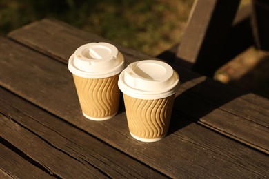Paper cups on wooden table outdoors. Coffee to go